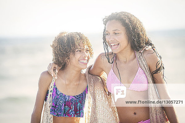 Fröhliche Freunde im Bikini am Strand spazieren