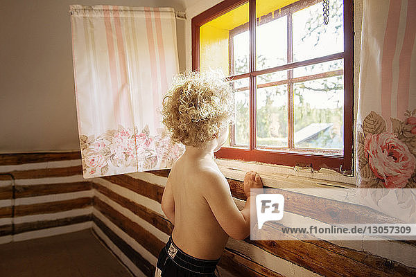 Boy looking through window in cottage