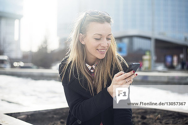 Smiling beautiful woman using phone in city