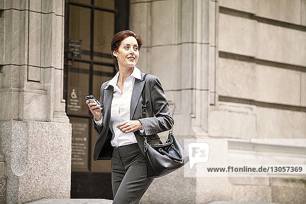 Happy businesswoman looking away while walking on city street