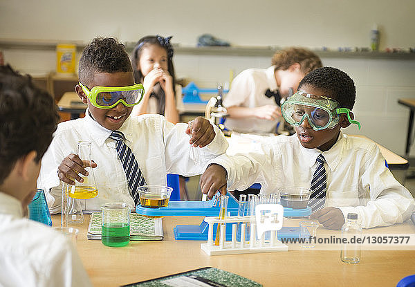 Schülerinnen und Schüler messen Chemikalien am Tisch im Labor