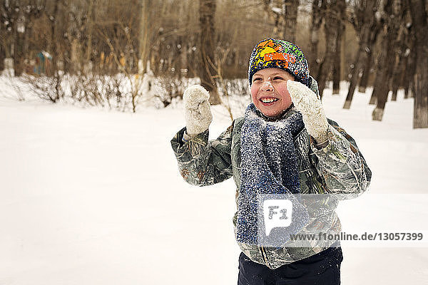 Happy boy playing with snow on field