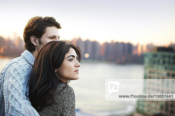 Young couple looking away against river