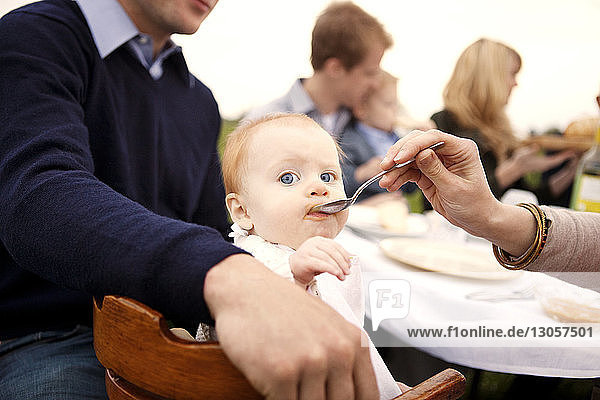 Ausgeschnittenes Bild einer Mutter  die ein Mädchen am Picknicktisch füttert