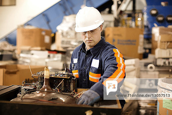 Male worker checking electrical equipment in recycling plant