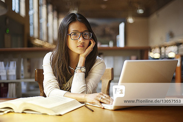 Portrait of woman using laptop computer while sitting in library