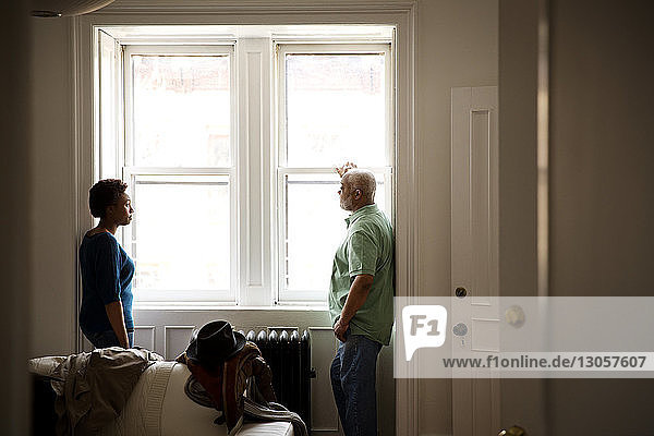 Father and daughter standing by window at home