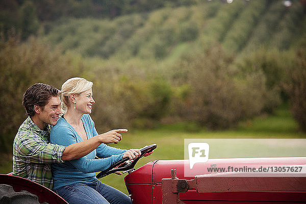 Man teaching woman to ride tractor