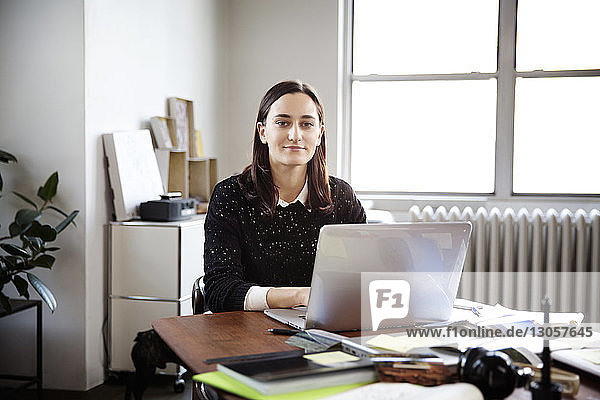 Porträt einer jungen Geschäftsfrau  die im Kreativbüro am Laptop arbeitet