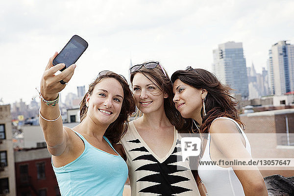 Happy friends taking selfie on building terrace