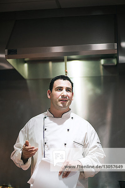 Chef holding hat while standing in commercial kitchen