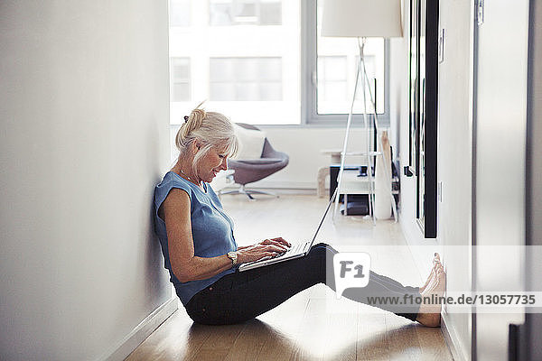 Seitenansicht einer älteren Frau  die zu Hause einen Laptop benutzt