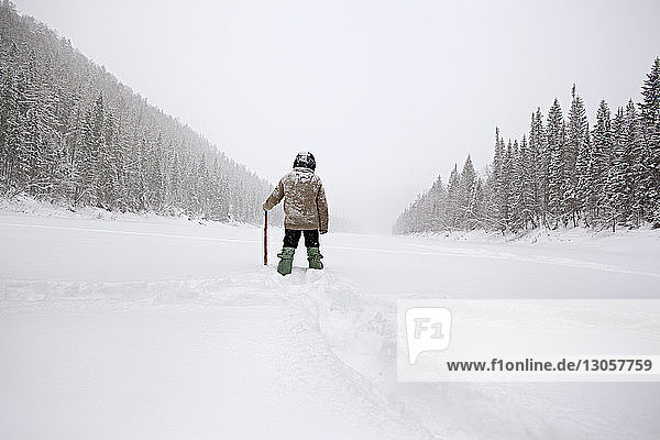 Rückansicht eines Mannes  der auf einem schneebedeckten Feld wandert