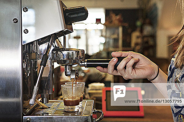Ausgeschnittenes Bild einer Frau  die die Kaffeemaschine im Café benutzt