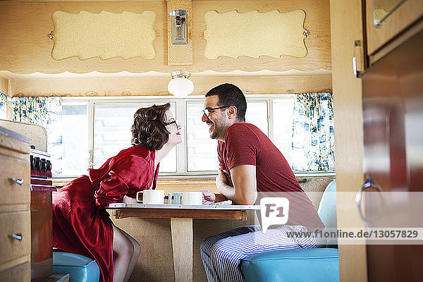Seitenansicht fröhliches Paar am Tisch sitzend im Wohnmobil