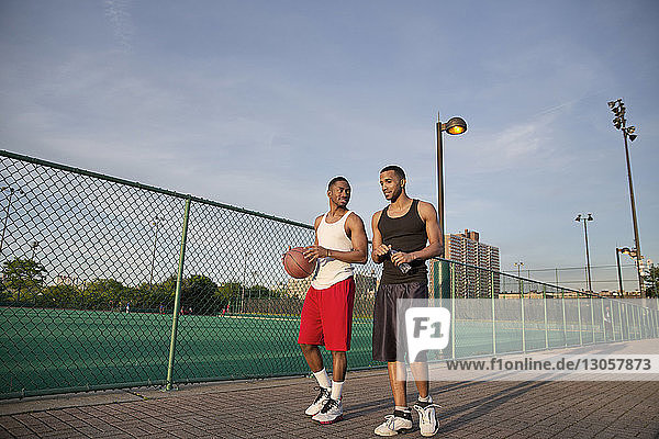 Basketballspieler unterhalten sich beim Laufen auf dem Platz gegen den Himmel