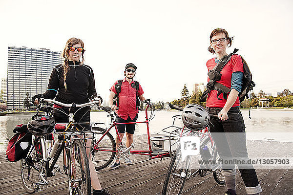 Portrait von Radfahrern mit Fahrrad  die auf einem Steg vor klarem Himmel stehen