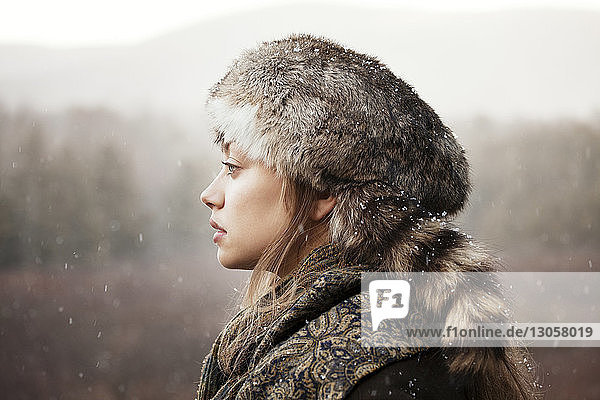 Thoughtful woman in warm clothing near forest