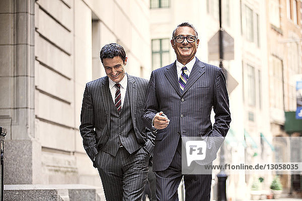 Happy businessmen walking on city street