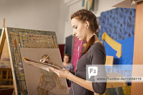 Junge Frau malt im Stehen im Kunstunterricht
