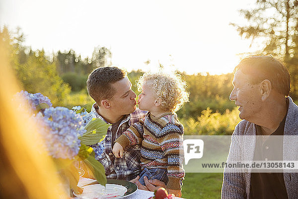 Father kissing son at picnic table on sunny day