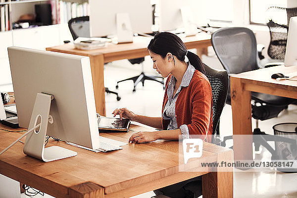 Businesswoman using tablet while sitting on chair at office