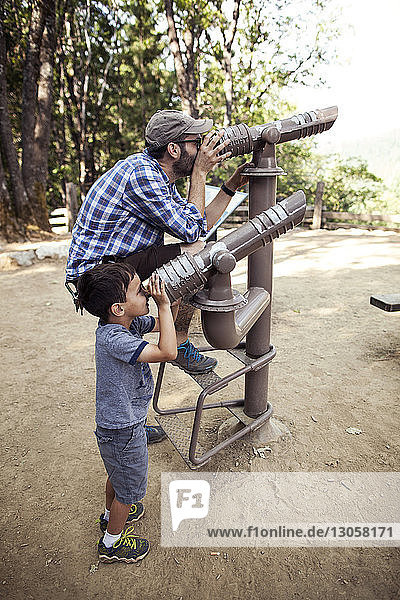 Vater und Sohn schauen durch Teleskope im Wald