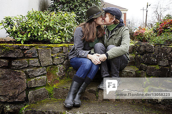 Couple rubbing noses while sitting steps in garden