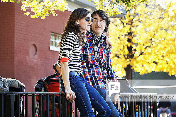 Couple with arm around leaning on railing