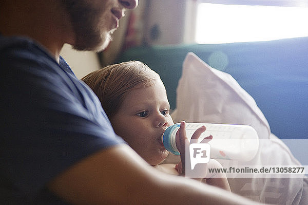 Nahaufnahme eines kleinen Jungen  der Milch trinkt  während er mit seinem Vater zu Hause sitzt
