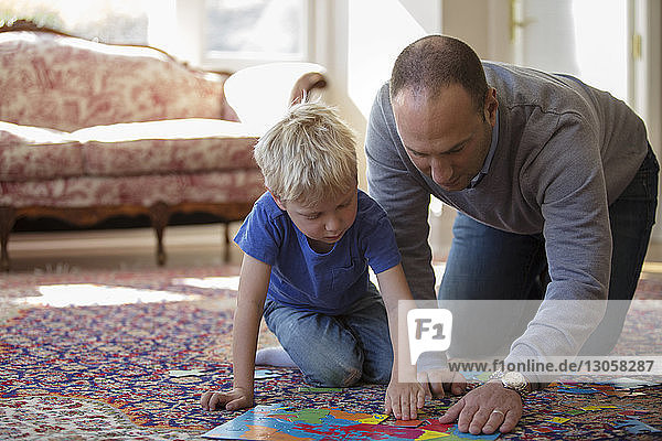 Vater und Sohn spielen zu Hause mit Puzzle auf dem Boden