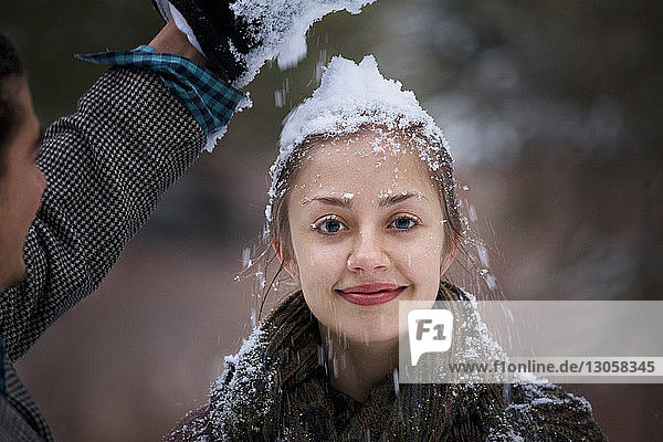 Man putting snow on girlfriend's head