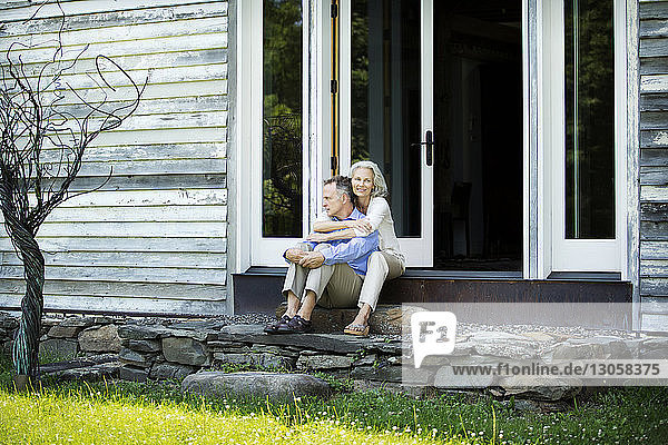 Ältere Frau umarmt Mann  während sie vor dem Haus sitzt