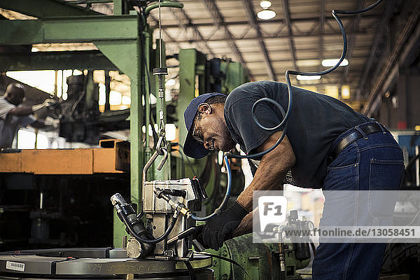Seitenansicht eines Arbeiters  der in der Metallindustrie Maschinen bedient