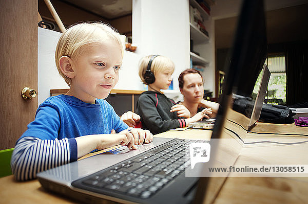 Kinder benutzen Laptop-Computer  während sie bei der Mutter zu Hause sitzen