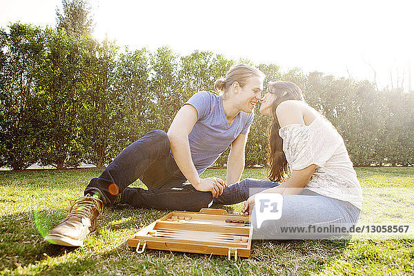 Romantic couple playing Backgammon game at grassy field
