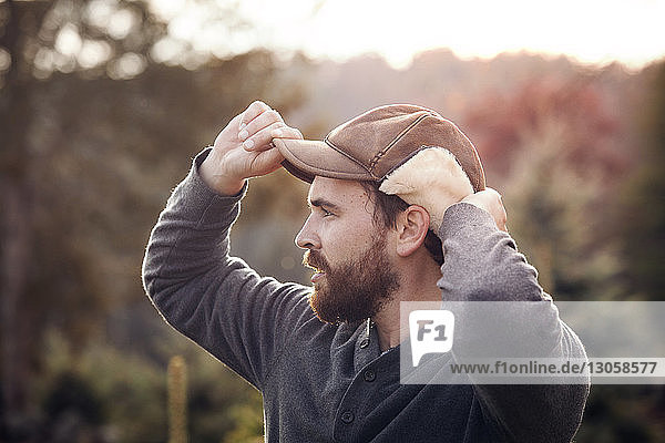 Man looking away while holding cap
