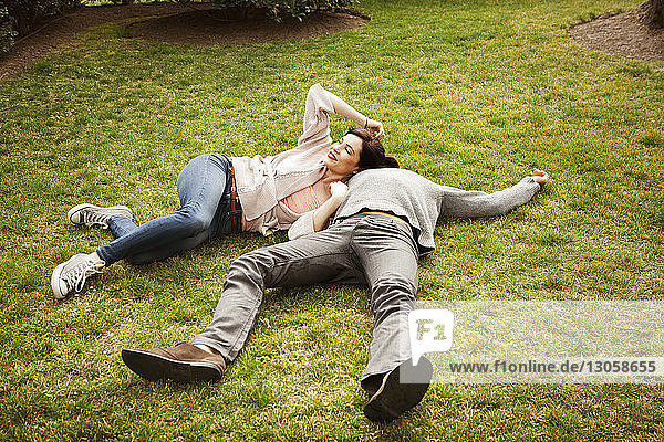 Mann und Frau liegen auf einem Grasfeld im Park