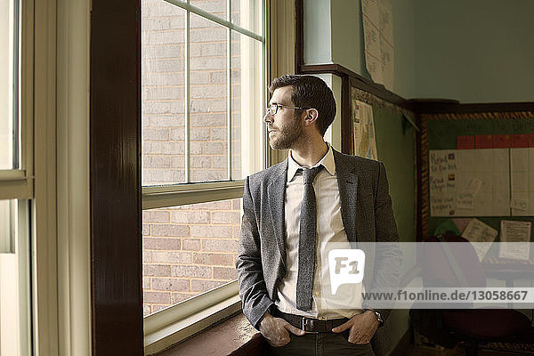 Thoughtful businessman looking through window while standing by window
