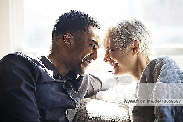 Glückliches Paar schaut sich an  während es auf dem Sofa sitzt