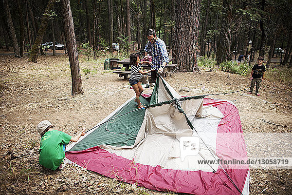 Familie stellt gemeinsam Zelt im Wald auf