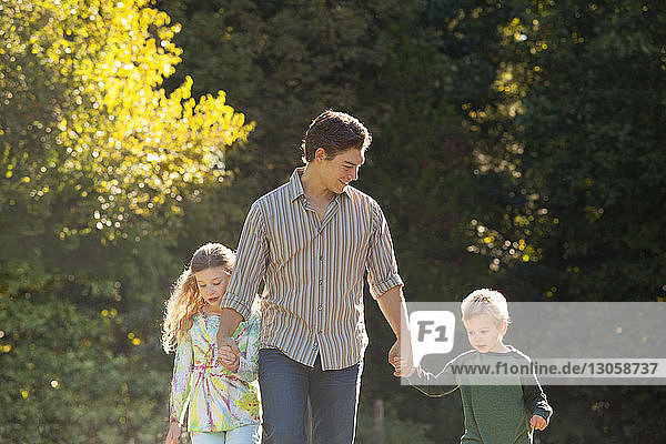 Father holding hands of children while walking