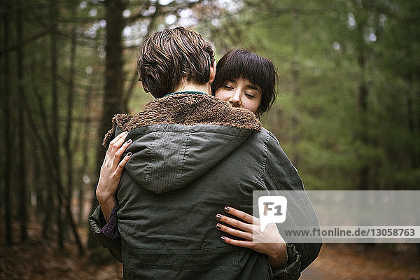 Couple embracing while standing in forest