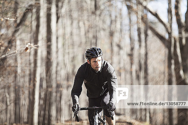 Fahrrad fahrender männlicher Sportler auf Straße im Wald