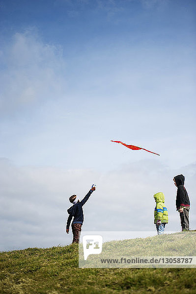 Low angle view of children looking at man flying kite