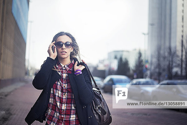 Junge Frau mit Sonnenbrille und Umhängetasche in der Stadt