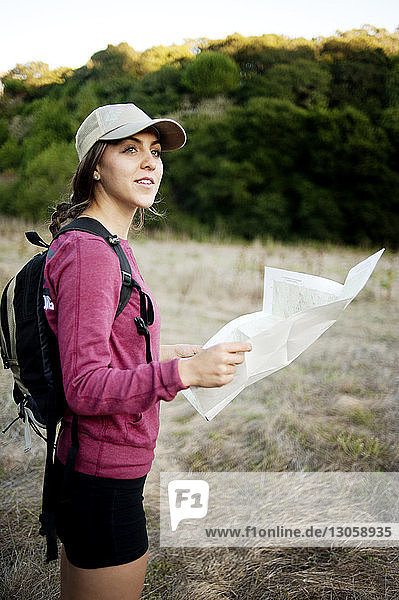Seitenansicht einer Wanderin  die die Karte hält  während sie auf dem Feld steht