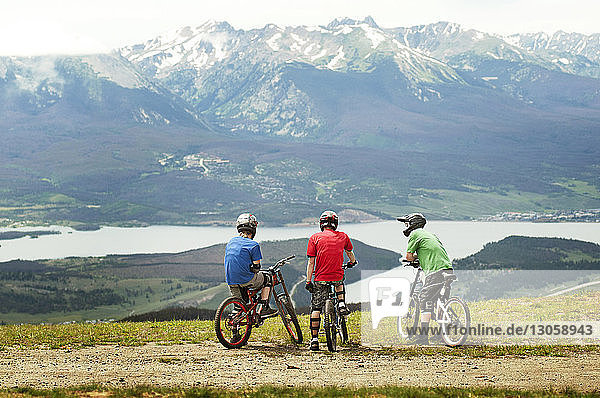 Rear view of cyclists on field against mountains