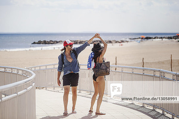 Happy couple dancing on boardwalk at beach during summer vacation