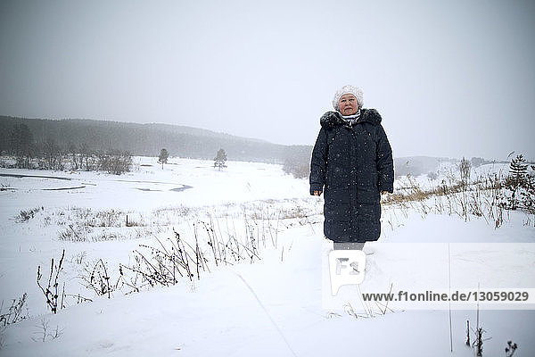 Portrait of woman in standing on snow covered field against clear sky